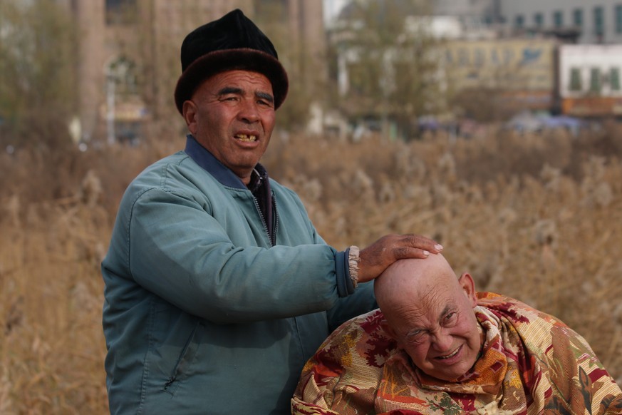 Coiffeur mitten im Park in Kashgar, China.