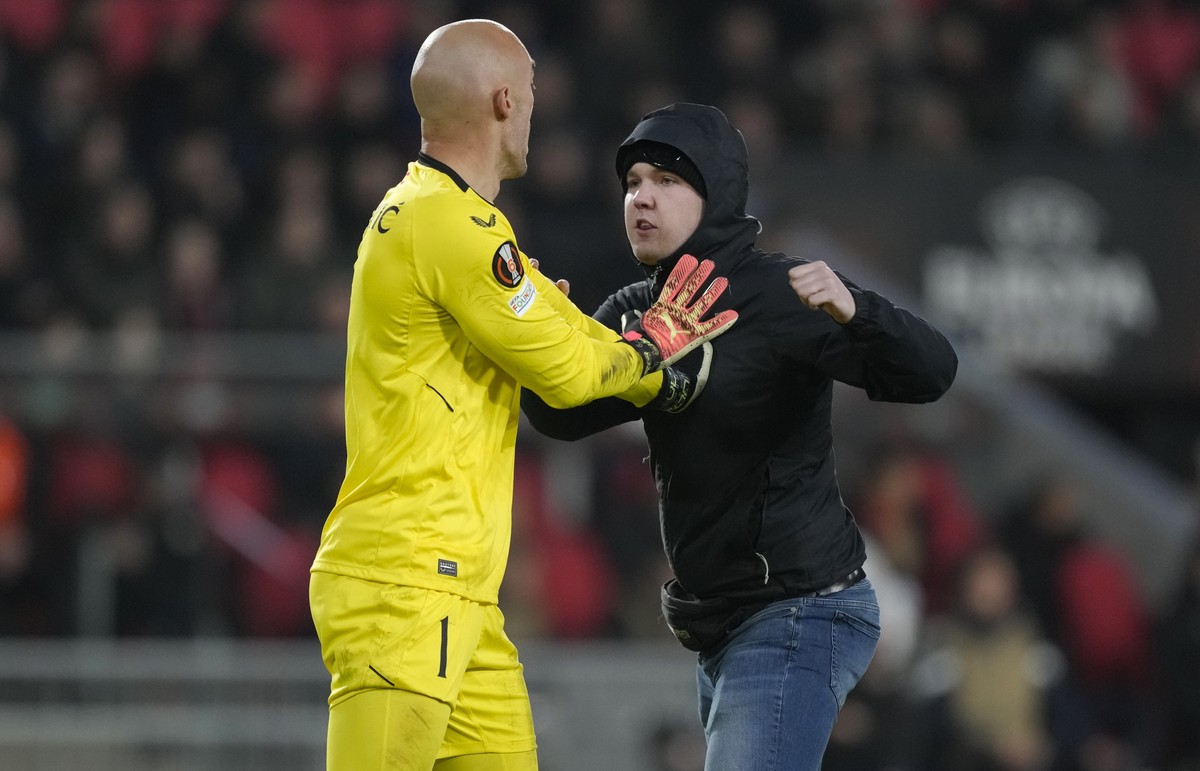 A PSV supporter attacks Sevilla's goalkeeper Marko Dmitrovic during the Europa League playoff second leg soccer match between PSV and Sevilla at the Philips stadium in Eindhoven, Netherlands, Thu ...
