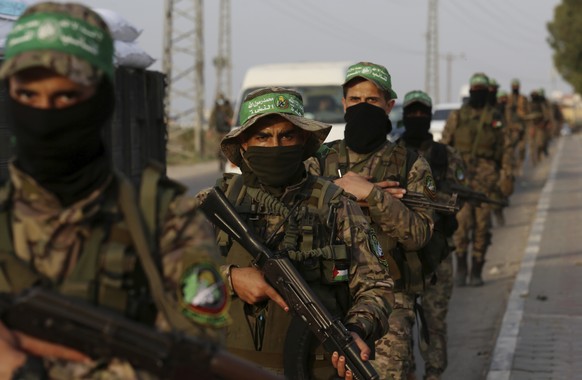 Masked militants from the Izzedine al-Qassam Brigades, a military wing of Hamas, march with their rifles along the main road of Nusseirat refugee camp, central Gaza Strip, Thursday, Oct. 28, 2021. Ara ...