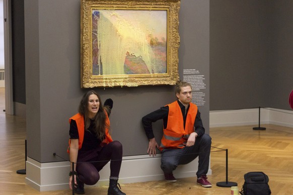 Climate protesters of Last Generation after throwing mashed potatoes at the Claude Monet painting &quot;Les Meules�� at Potsdam���s Barberini Museum on Sunday Oct. 24, 2022, to protest fossil fuel ext ...