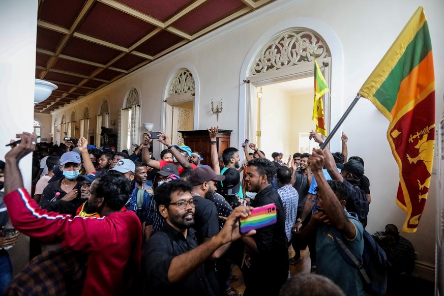 epa10061732 Protesters cheer inside the president&#039;s official residence premises in Colombo, Sri Lanka, 09 July 2022. Thousands of protesters broke through police barricades and stormed the presid ...