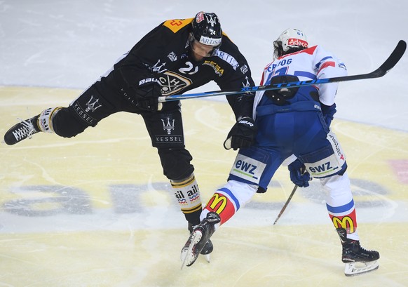 LuganoÃs player Jani Lajunen, left, fights for the puck with Zurich&#039;s player Fabrice Herzog, right, during the first match of the playoff final of National League between HC Lugano and ZSC lions ...