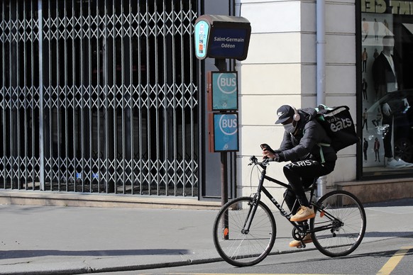 FILE - In this March 19, 2020 file photo, a food delivery service man rides his bike in Paris. Some 19 meal delivery companies in France including Uber Eats and Deliveroo have pledged to the French go ...