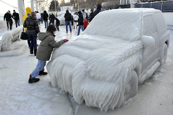 A young man walks along an ice covered car on the iced waterside promenade at the Lake Geneva in Versoix, Switzerland, Sunday, February 5, 2012. A cold spell has reached Europe with temperatures plumm ...