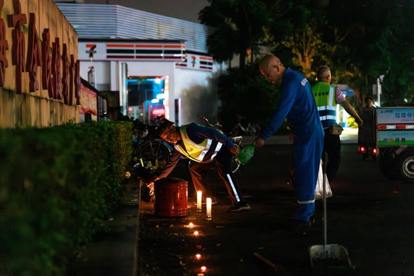 epa11716836 Workers remove flowers and candles left by mourners for the victims of a car ramming incident, at the entrance to the Zhuhai Sports Center in Zhuhai, China, 12 November 2024. According to  ...