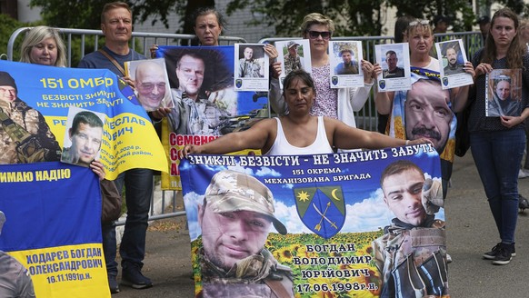 Family members of Ukrainian prisoners hold banners and photos of servicemen in captivity ahead of an exchange of prisoners between Russia and Ukraine, in Chernyhiv region, Ukraine, Friday, May 23, 202 ...
