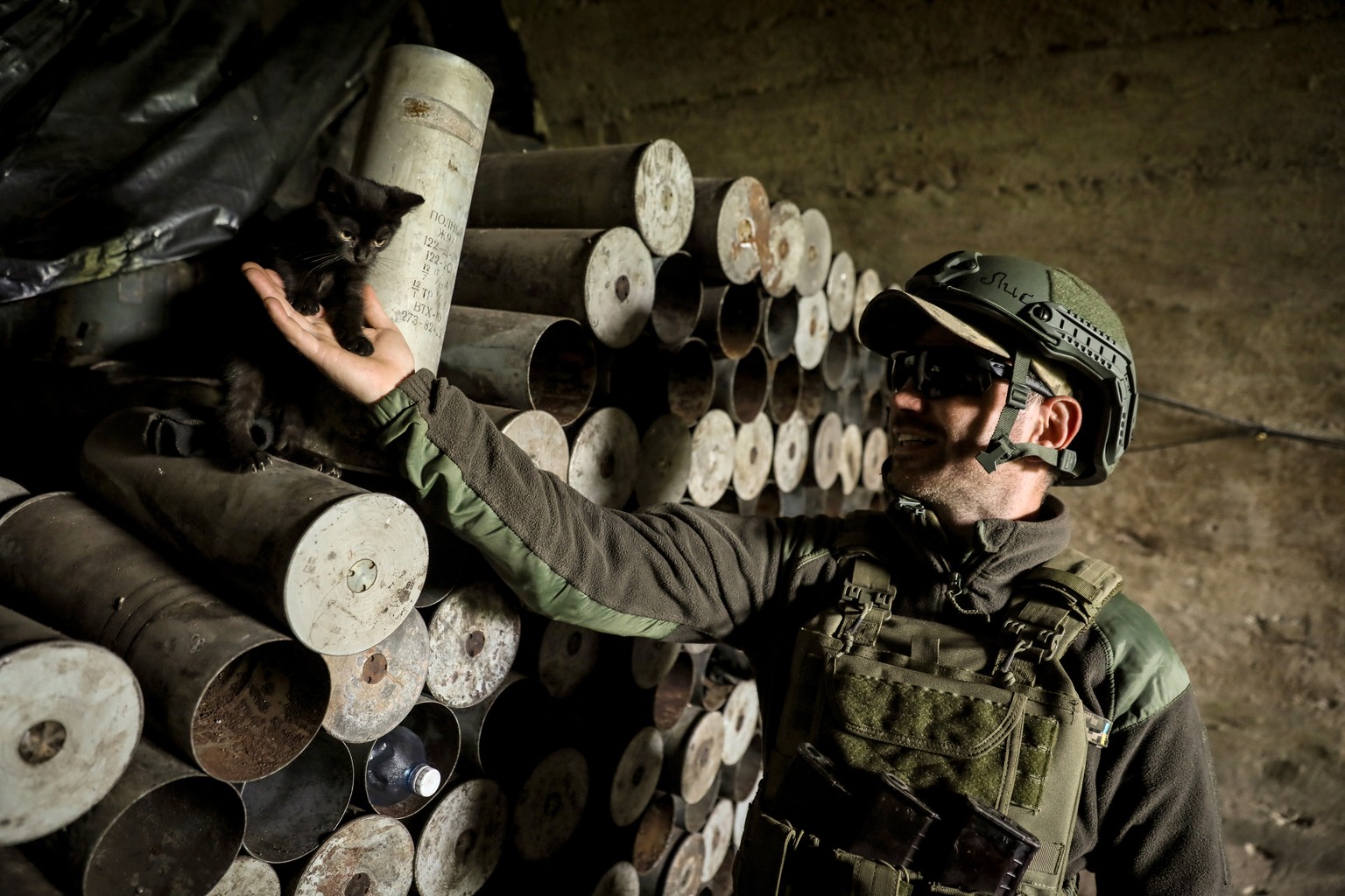 epa10648122 A member of the 10th Separate Mountain Assault Brigade &#039;Edelweiss&#039;, a unit of the Ukrainian Ground Forces, pets a cat next to artillery shells at an undisclosed location in the B ...