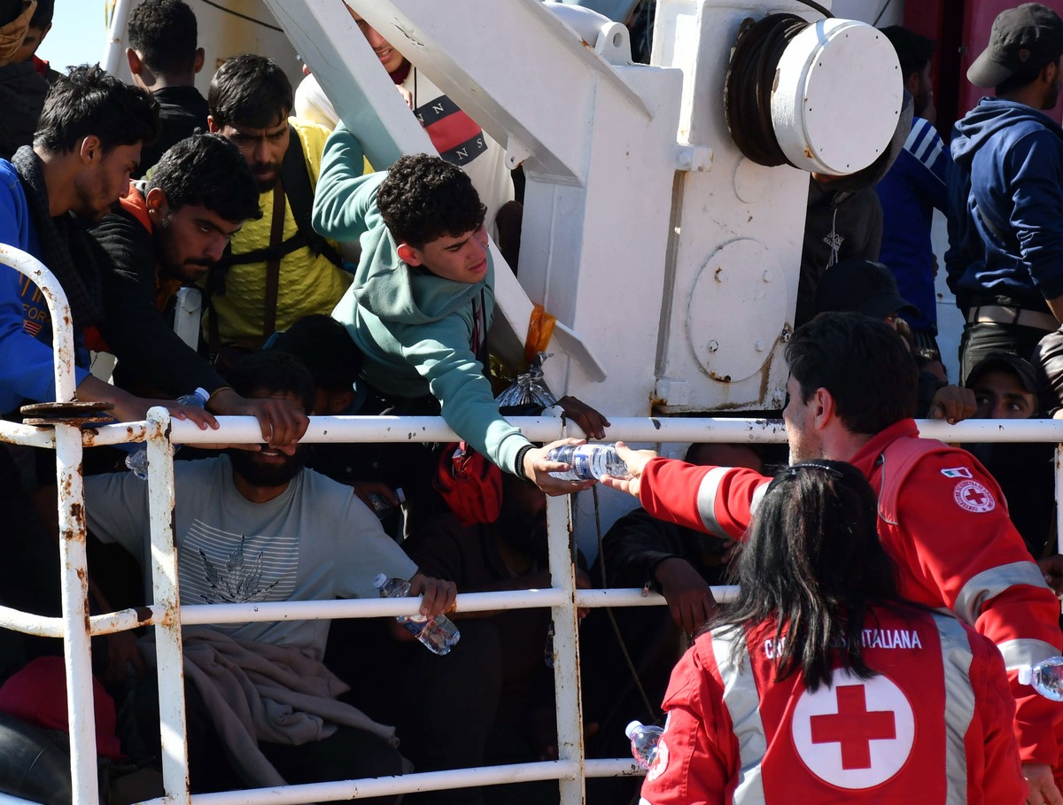 epa10569682 A migrant receives water from medical staff after arriving in the port of Catania, Italy, 12 April 2023. The vessel was escorted by the 'Nave Peluso' of the Coast Guard on the sa ...