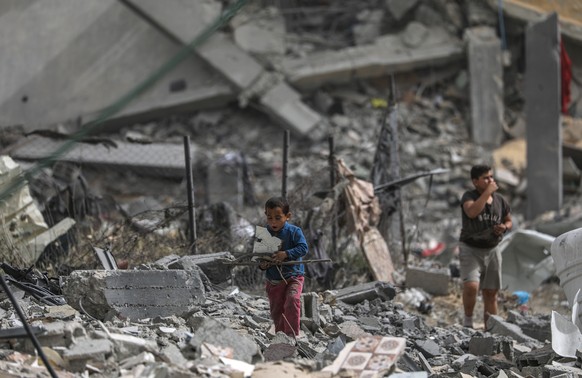 epa11286404 Palestinian children walk among the rubble after returning to Al Nusairat refugee camp following the Israeli army?s withdrawal from the area, southern Gaza Strip, 18 April 2024. More than  ...