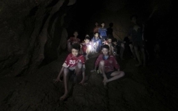 FILE - This Monday, July 2, 2018, file image released by Tham Luang Rescue Operation Center, shows the missing boys and their soccer coach as they were found in a dark, partially flooded cave, in Mae  ...