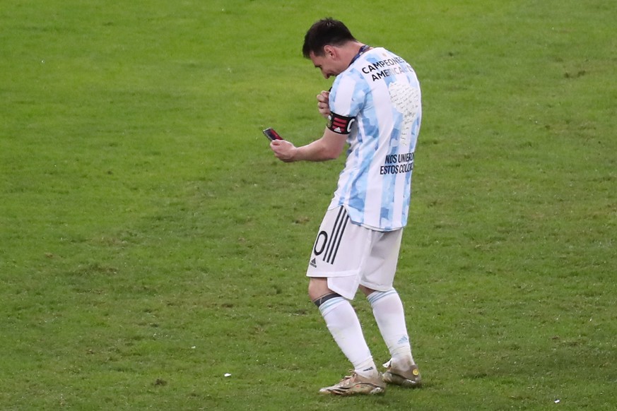 epa09336515 Argentina&#039;s Lionel Messi speaks on his cellphone as he celebrates their victory against Brazil after the Copa America 2021 final between Argentina and Brazil at the Maracana Stadium i ...