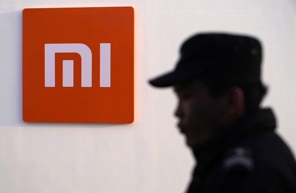 epa07382403 A security guard stands beside a logo of Xiaomi during the Xiaomi product launch ceremony in Beijing, China, 20 February 2019. Xiaomi releases its new mobile phone products 'Mi 9', 'Mi 9 E ...