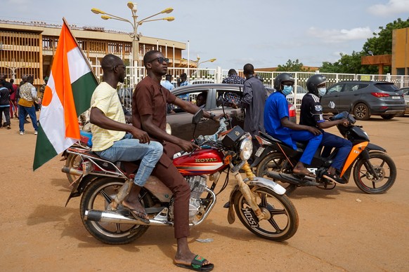 epa10788184 Two men on a motorcycle display a Niger flag as they join a rally at a stadium in Niamey, Niger, 06 August 2023. Thousands of pro-junta supporters gathered in a stadium to show their suppo ...