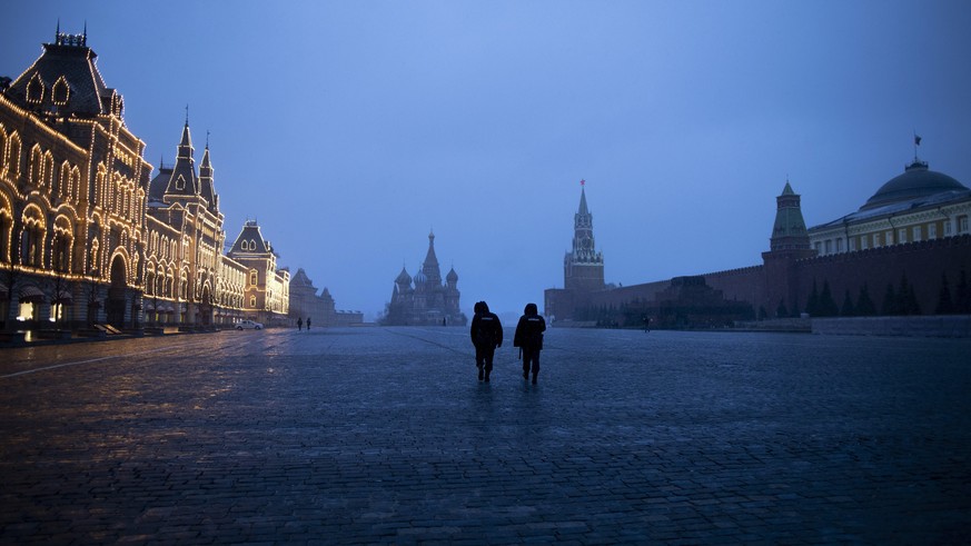 Two police officers patrol an almost empty Red Square, with St. Basil&#039;s Cathedral, center, and Spasskaya Tower and the Kremlin Wall, right, at the time when its usually very crowded in Moscow, Ru ...