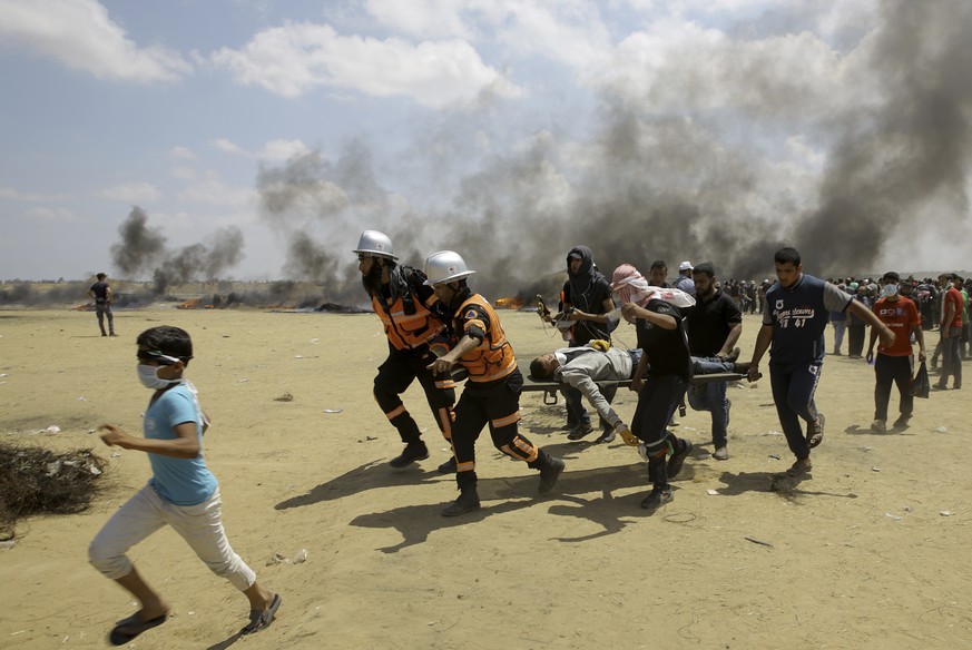 FILE - In this Monday, May 14, 2018 file photo, Palestinian medics and protesters evacuate a wounded youth during a protest at the Gaza Strip&#039;s border with Israel, east of Khan Younis, Gaza Strip ...