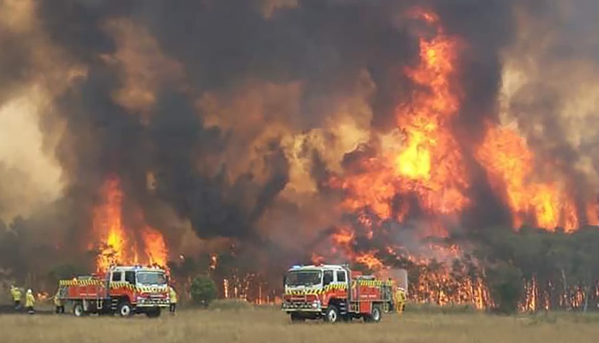 In this image dated Dec. 30, 2019, and provided by NSW Rural Fire Service via their twitter account, firefighters are seen as they try to protect homes around Charmhaven, New South Wales. Wildfires bu ...