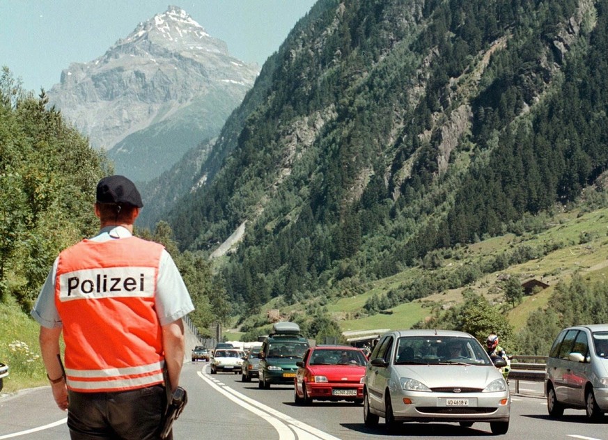 Am Gotthard sorgte der Ferienverkehr am Samstag, 17. Juli 1999 auf der gesamten Bergstrecke der A2, hier bei Wassen, fuer einen bis zu 15 Kilometer langen Stau. Ein Kantonspolizist warnt vor der " ...