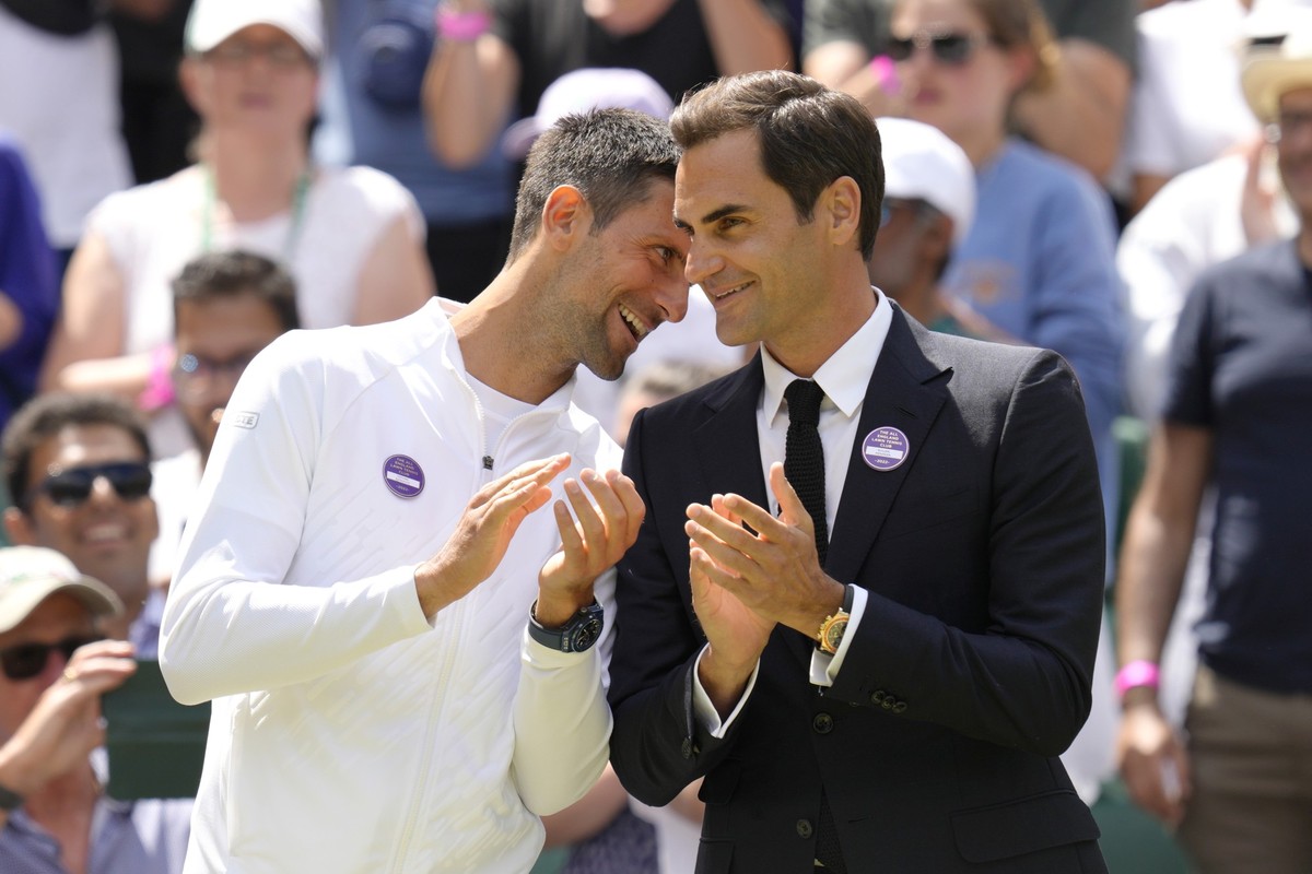 Serbia's Novak Djokovic and Switzerland's Roger Federer speak during a 100 years of Centre Court celebration on day seven of the Wimbledon tennis championships in London, Sunday, July 3, 202 ...