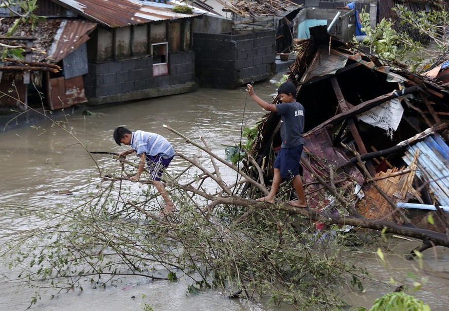 epa05688298 Filipino children clear a toppled tree at a flooded village in the typhoon-hit town of Milaor, Camarines Sur, Philippines, 26 December 2016. According to Office of Civil Defense (OCD) repo ...