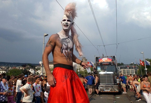 A chic, fully clothed participant in the annual Street Parade walks in front of a Love Mobile in the city of Zurich, Saturday, August 7, 2004. About a million people took to the streets to enjoy the…