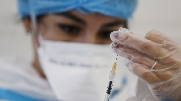 A nurse prepares a syringe with the COVID-19 vaccine at Santa Maria Della Pieta hospital in Rome, Monday, Dec. 28, 2020. 80 healthcare workers received Covid-19 vaccinations on Monday in a Rome hospit ...