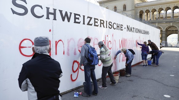 Aktivisten reinigen die davor mit dem Spruch &quot;Bitte erinnere dich, wozu wir dich gegruendet haben&quot; versprayte Wand vor der Schweizerischen Nationalbank, am Freitag, 27. April 2018 in Bern. ( ...