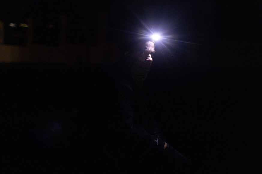 epa10277573 A man with a headlight walks while the street lights are switched off, in downtown Kyiv, Ukraine, 31 October 2022. Scheduled power cuts were introduced in Kyiv, power operator Ukrenergo sa ...
