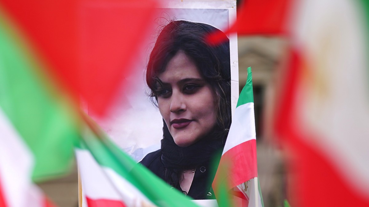 epa10217479 A portrait of Mahsa Amini stands between Iranian national flags during a 'Solidarity with the civil uprising in Iran' rally at Bebel Platz square in Berlin, Germany, 01 October 2 ...