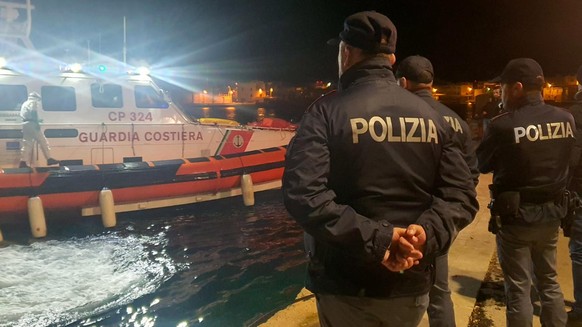 epa10445200 Police officers wait on the quay of the port for the boat with the bodies of 8 migrants in Lampedusa, Sicily, Italy, February 03, 2023. The soldiers of a Coast Guard patrol boat rescue ...