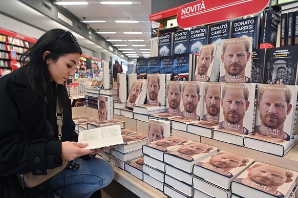 epa10400222 A person reads a copy of Prince Harry&#039;s memoir &#039;Spare&#039; displayed at the Mondadori bookstore in Viotti street, in Turin, Italy, 11 January 2023. The publisher of the autobiog ...