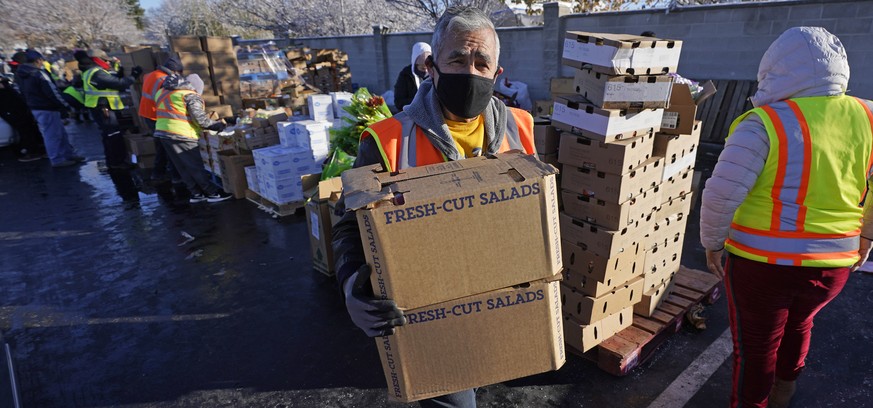 A volunteer carries food to waiting cars at the Utah Food Bank&#039;s mobile food pantry Thursday, Nov. 12, 2020, in West Valley City, Utah. As coronavirus concerns continue, the need for assistance h ...