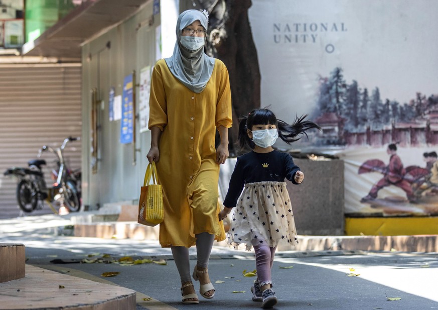 Kind und Mutter mit Gesichtsmaske: Bei rund 100 Kindern ist eine mysteriöse Krankheit aufgetreten.