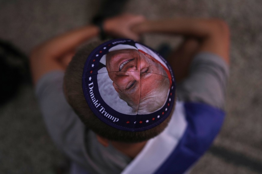 A Jewish man wears a kippah printed with the image of U.S. President Donald Trump during a gathering at a plaza known as hostages square in Tel Aviv, Israel, Monday, Oct. 13, 2025, before the release  ...