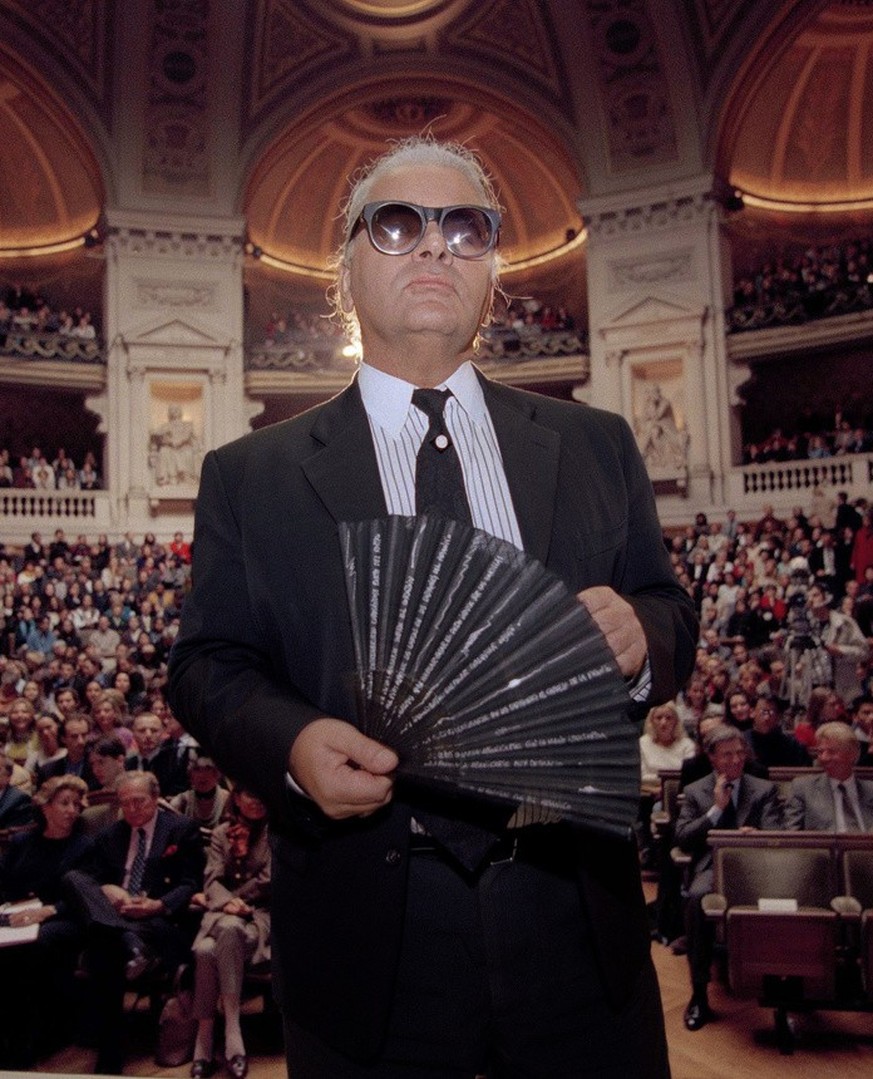 Karl Lagerfeld, the German fashion designer for Chanel, holds his fan as he enters the main auditorium at the Sorbonne, the oldest and most famous university in France, Oct. 18, 1994. Lagerfeld fielde ...