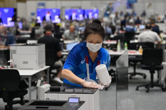 epa09354408 An employe disinfects a workstation at the Olympic Media Center in Tokyo, Japan, 20 July 2021. The pandemic-delayed 2020 Summer Olympics are schedule to open on July 23 with spectators ban ...