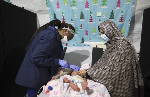 Jemimah Sampong, a licensed practical nurse, attends to a 9-day-old child as her mother looks on inside the pediatric ward of a medical treatment facility at Joint Base McGuire-Dix- Lakehurst in Trent ...