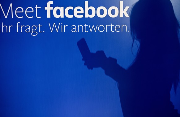 epa07713904 (FILE) - A shadow of a person using smartphone is cast on wall at the Facebook pop-up store in Cologne, Germany, 16 November 2018 with text on glas window reading &#039;Meet facebook. You  ...
