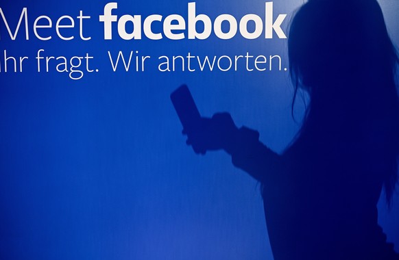 epa07713904 (FILE) - A shadow of a person using smartphone is cast on wall at the Facebook pop-up store in Cologne, Germany, 16 November 2018 with text on glas window reading &#039;Meet facebook. You  ...