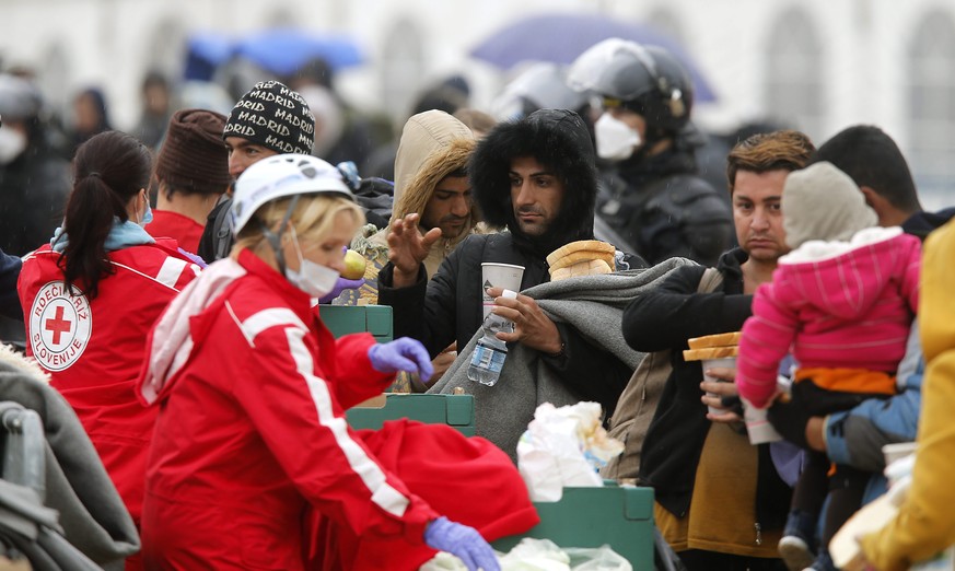 Helferinnen des slowenischen Roten Kreuzes verteilen Ende Oktober 2015 Wasser und Brot an Flüchtlinge in einem provisorischen Camp in Dobova.