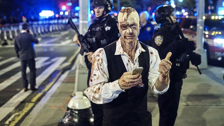 A reveler gets his picture taken by a friend in front of heavily armed police during the Greenwich Village Halloween Parade, Tuesday, Oct. 31, 2017, in New York. (AP Photo/Andres Kudacki)