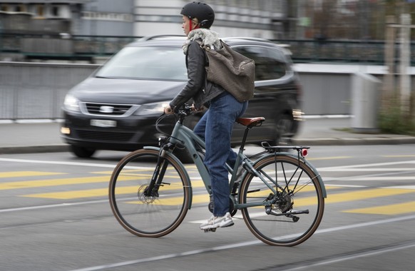 Eine E-Bike-Fahrerin mit Helm kreuzt das Limmatquai in Zuerich am 5. Oktober 2020. (KEYSTONE/Gaetan Bally)