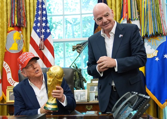 FILE - President Donald Trump holds the FIFA World Cup Winners Trophy as FIFA President Gianni Infantino looks on during an announcement in the Oval Office of the White House, Aug. 22, 2025, in Washin ...