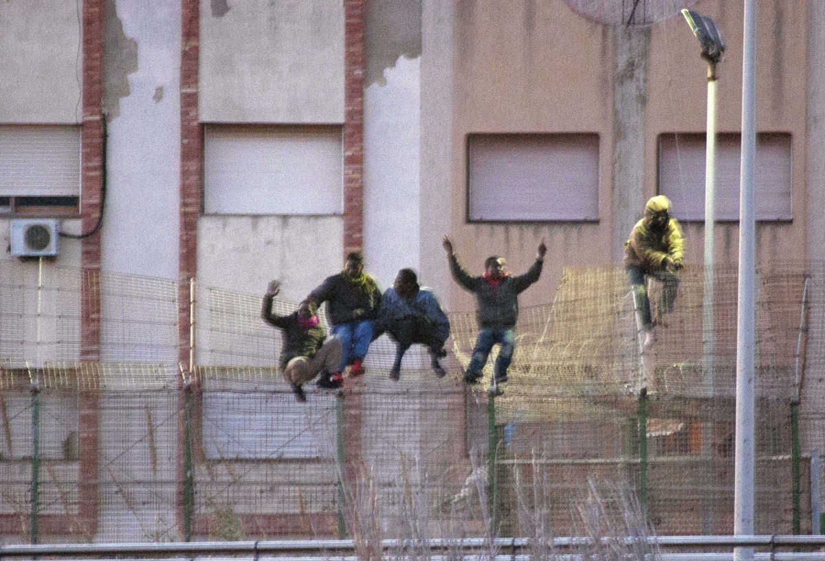 Immigrants scale over a border fence separating Spain's north African enclave Melilla from neighboring Morocco February 28, 2014. Over 200 immigrants entered Melilla through the Beni-Enzar border ...