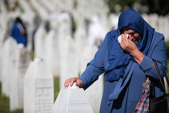 epa10064792 A Bosnian Muslim woman visits gravestones during a funeral ceremony for fifty newly-identified Bosnian Muslim victims, at the Potocari Memorial Center and Cemetery in Srebrenica, Bosnia an ...