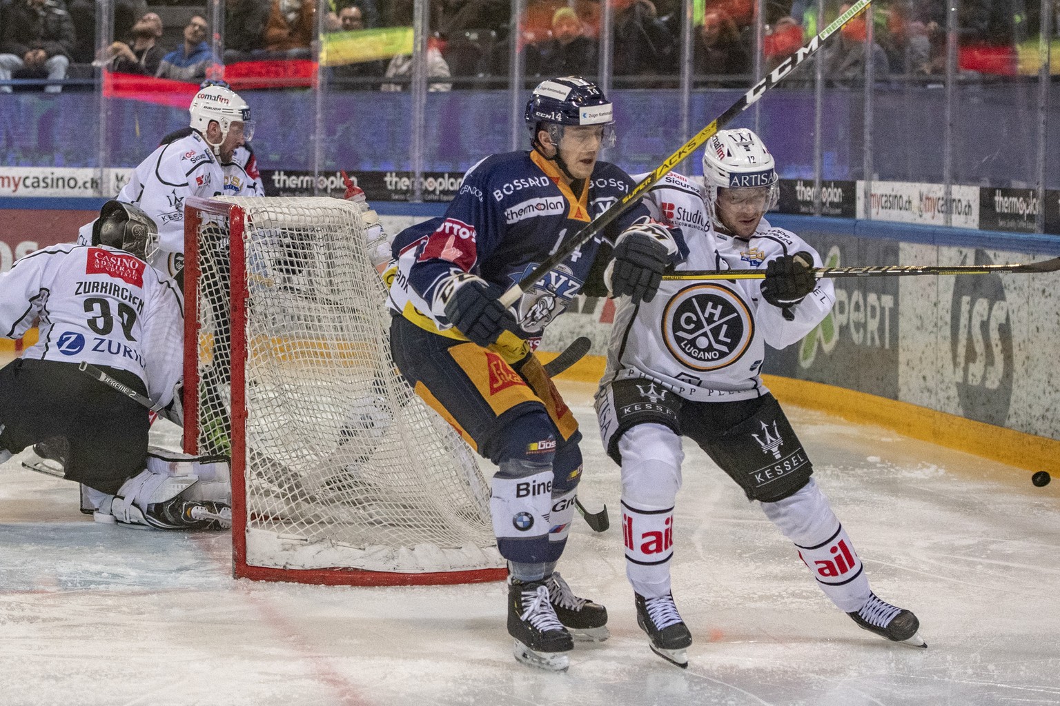 Torhueter Sandro Zurkirchen, links, und Dominic Lammer, rechts, von Lugano im Spiel gegen Livio Stadler, mitte, von Zug beim Eishockey Meisterschaftsspiel in der Qualifikation der National League zwis ...