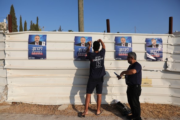 epa07847785 Activists hang a poster of Yisrael Beitenu political party leader and former Israeli defense Minister Avigdor Lieberman during the Israeli legislative elections outside a polling station i ...