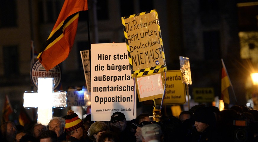 epa05018335 Supporters of Pegida (Patriotic Europeans Against the Islamisation of the Occident) hold up signs which read &#039;The government goes down, but Germany doesn&#039;t&#039; (R) and &#039;He ...