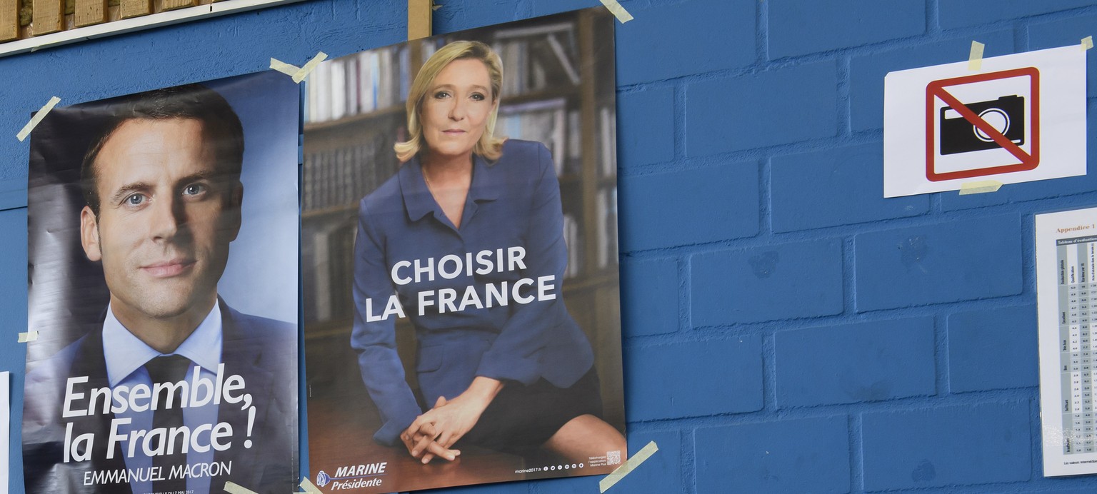 Posters showing French National Front political party leader Marine Le Pen, right, and Emmanuel Macron, left, head of the political movement En Marche at a polling station for the second round of the  ...