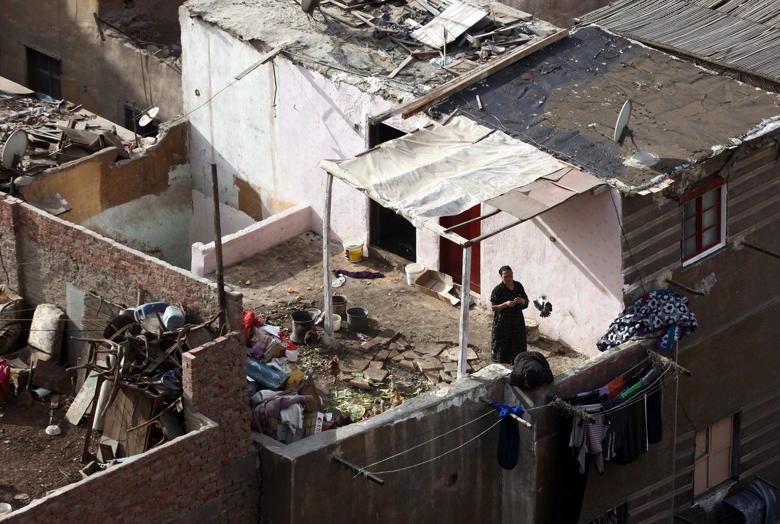 epa03584511 A woman watches from her balcony in the Ramlet Bulaq's slum in Cairo, Egypt, February 14, 2013. The residents of Ramlet Bulaq live in dilapidated shacks and lack basic amenities, such as r...