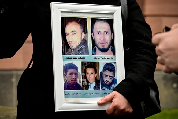epa09682156 Yasmen Almashan shows a picture of her brothers, who died in Syria, prior to the verdict against a former Syrian secret police officer at the Higher Regional Court in Koblenz, Germany, 13  ...